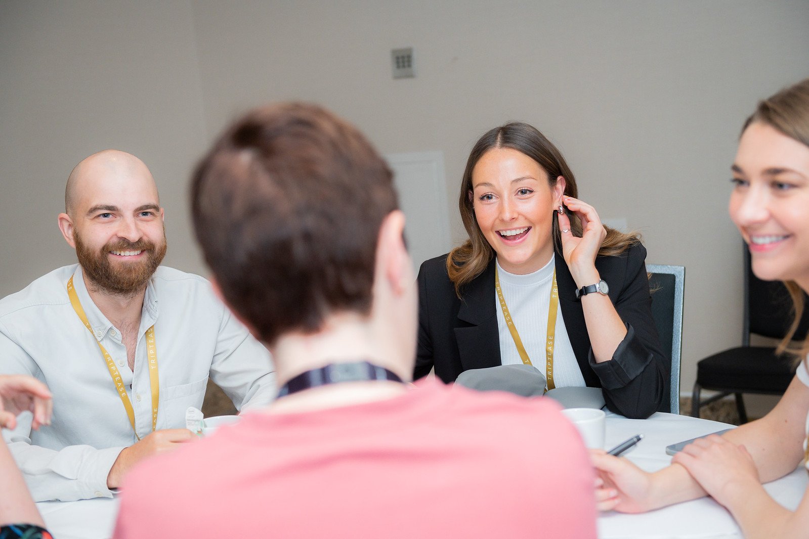 Attendees laughing together around a table during a working session at the Direct Booking Summit